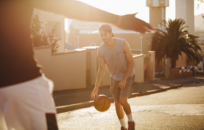 Young man playing with basketball on the street