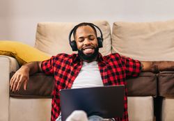 Black man in casual clothes using laptop at home.