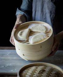 Cook preparing buns in bamboo steamer