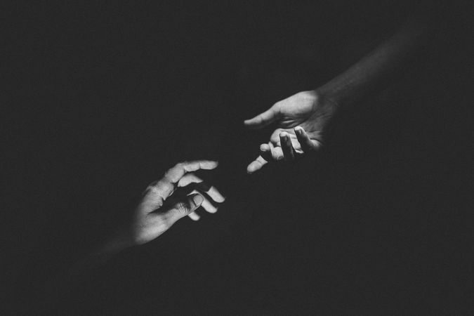 Grayscale photo of two hands about to hold each other