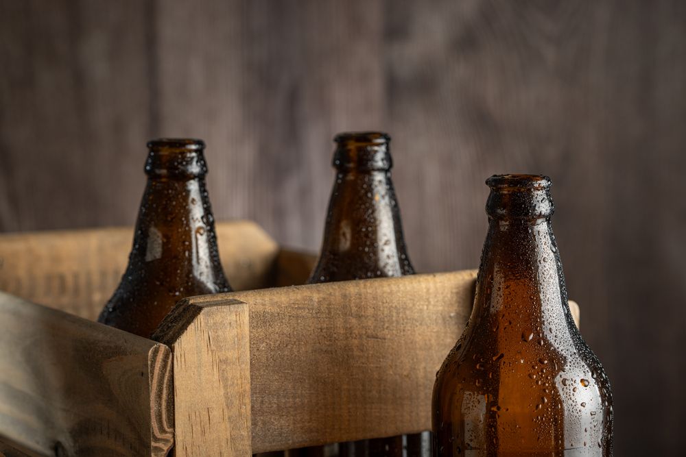 Empty amber beer bottles on rustic wooden background.