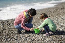 Woman and girl collecting rocks on a cold beach
