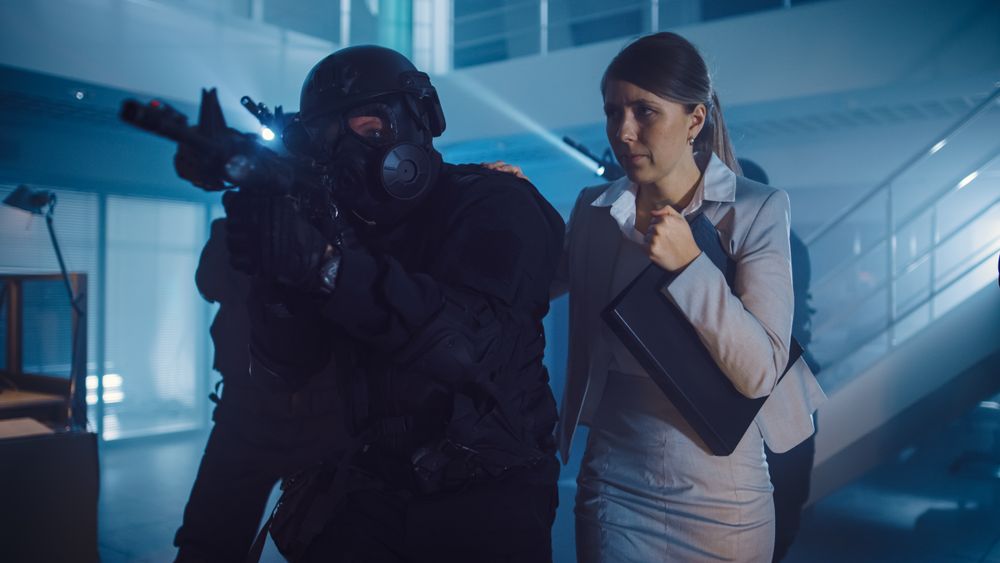 Masked Squad of Armed SWAT Police Officers Rescue a Female Hostage in a Dark Seized Office Building with Desks and Computers.