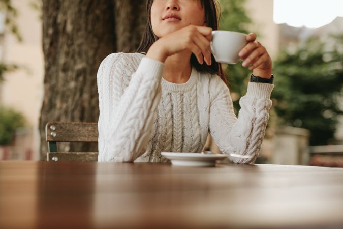 Cropped shot of young woman holding a cup of tea at cafe.