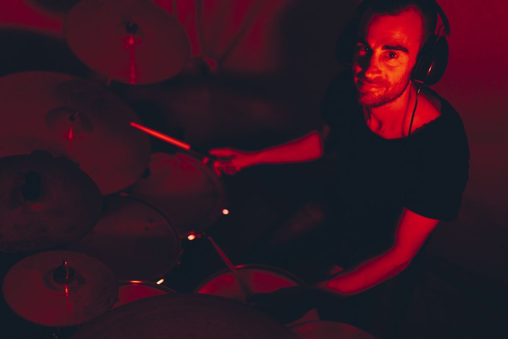 Man with drumsticks playing on drums in redness