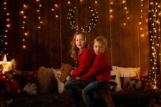 Siblings sitting in wooden horse swing during christmas