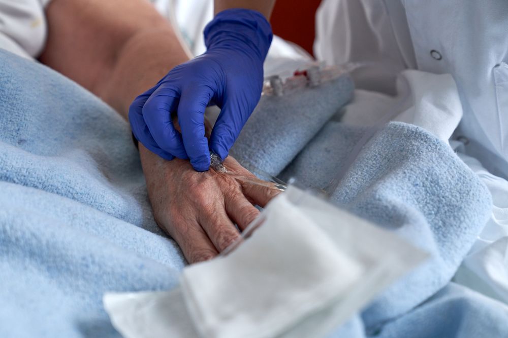 Unrecognizable doctor attaching catheter on hand of patient
