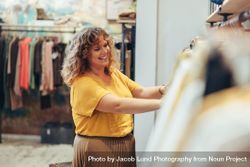 Saleswoman arranging clothes in rack of her fashion store 0Pa9g5