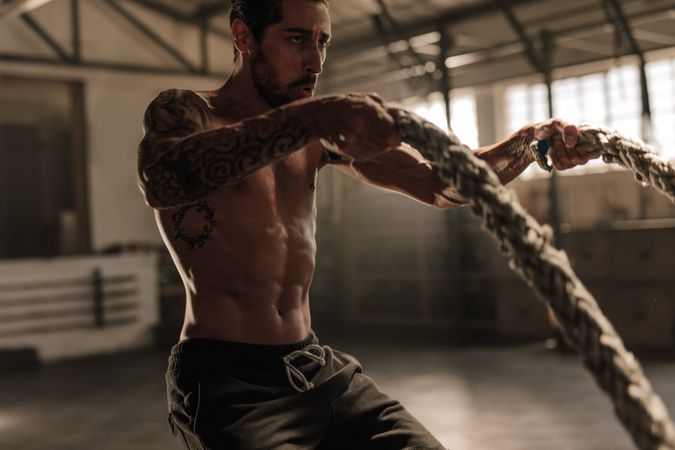 Athlete working out with battle ropes at gym