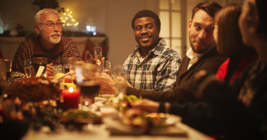 Portrait of a Young Black Man Proposing a Toast at a Christmas Dinner Table.