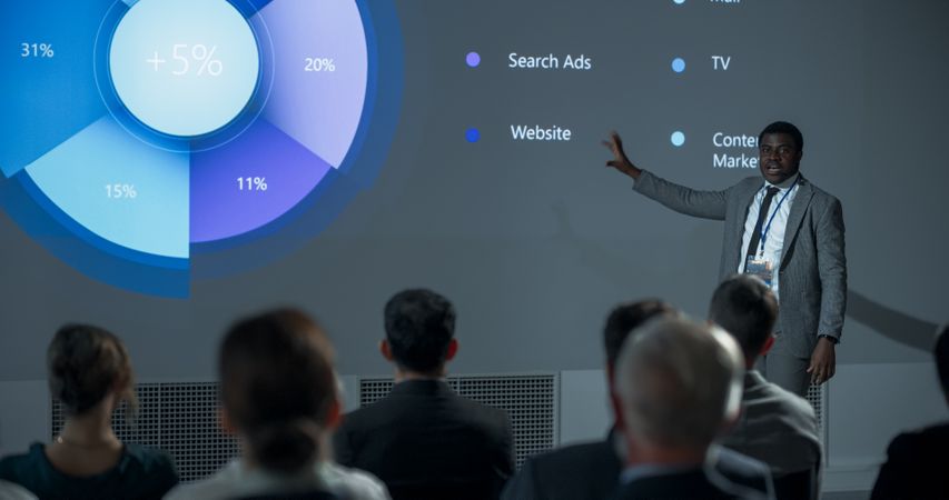 Corporate Event: Black Male Marketing Director Giving Presentation To Colleagues or Investors In Conference Room Of Innovative Startup Office.
