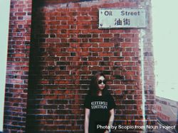 Woman in dark t-shirt standing beside brick wall 4A9eQ4