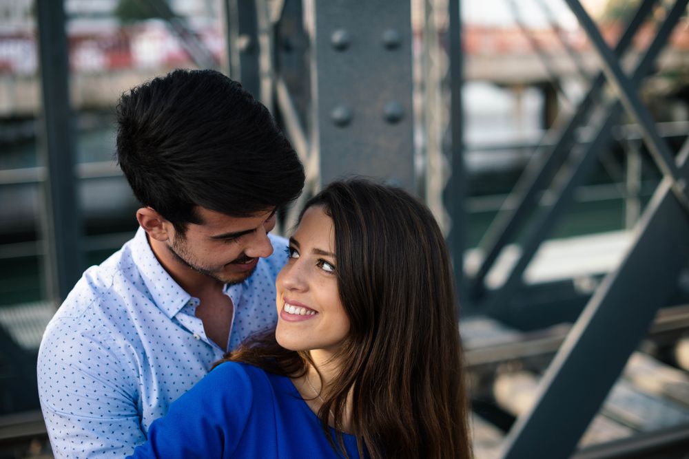 Amorous couple bonding on railway under bridge