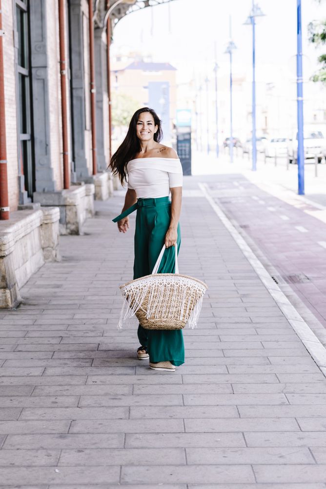 Young happy trendy woman walking in city against blue door