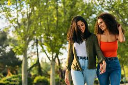 Female couple walking holding hands in a park.