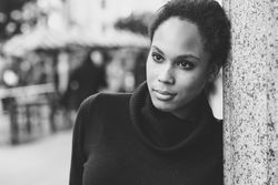 B&W portrait of calm woman in sweater outside with people in the background, copy space