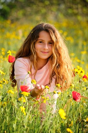 Girl relaxing amidst flowers in meadow