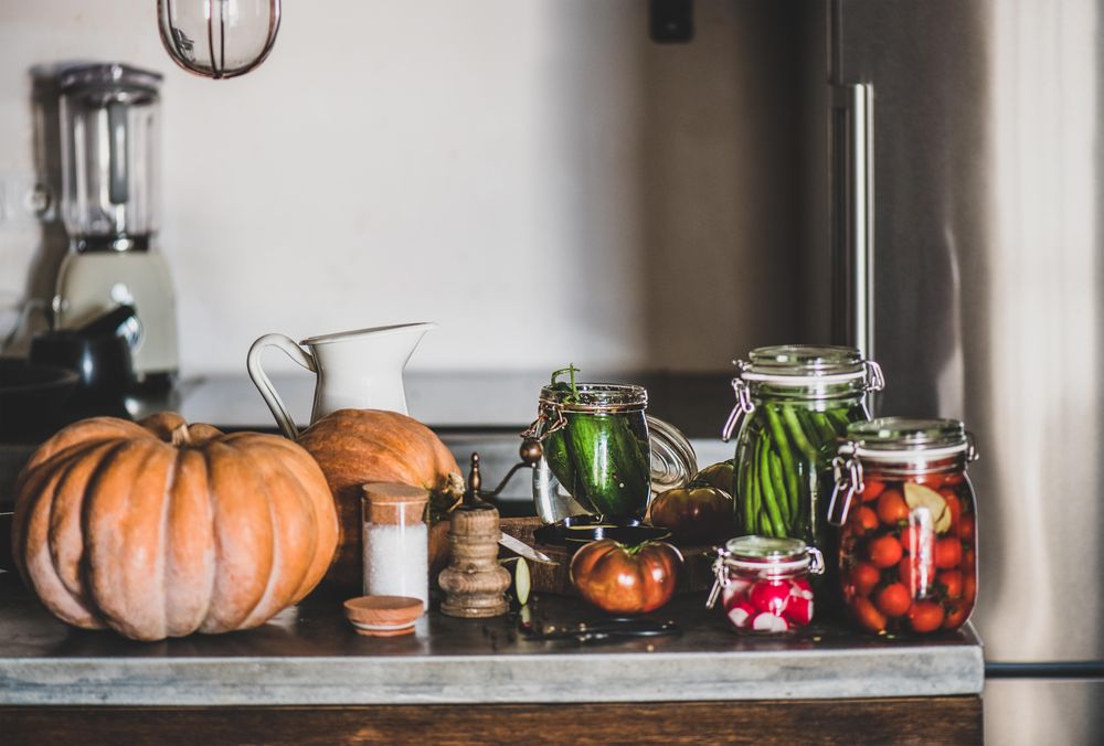 Rustic kitchen with pickled vegetables, spices and herbs on counter