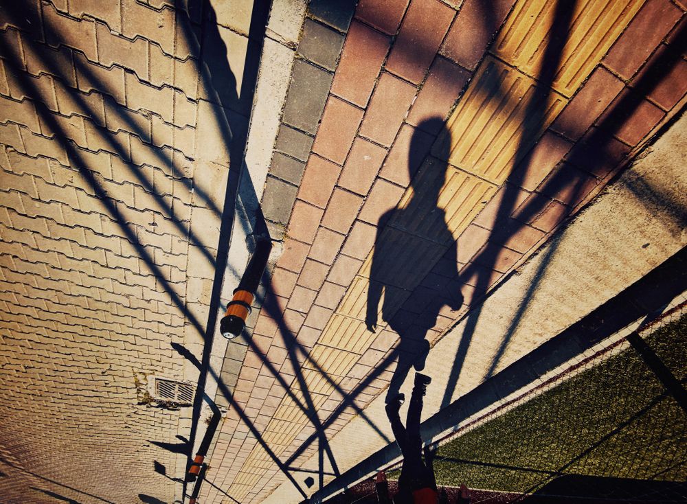 Shadow of person walking on sidewalk