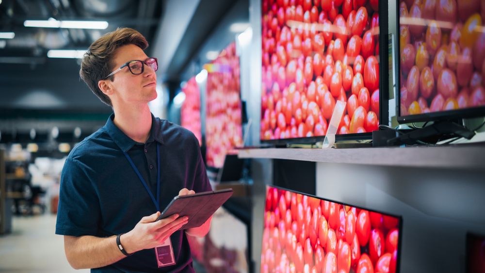 Young Sales Manager in Home Electronics Store Expertly Manages Operations Using Tablet.