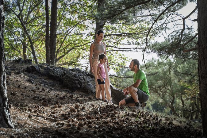 Father teaching daughter in pine forest while enjoying peaceful family hike