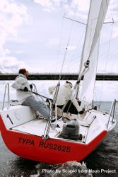 Two people on light and red sail boat 4Ao660