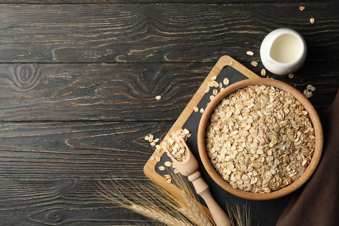 Composition with oatmeal flakes and milk on wooden background