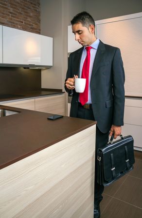 Sleepy businessman holding cup of coffee in the kitchen before go to work