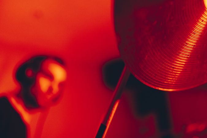 Man with drumsticks playing on drums in redness