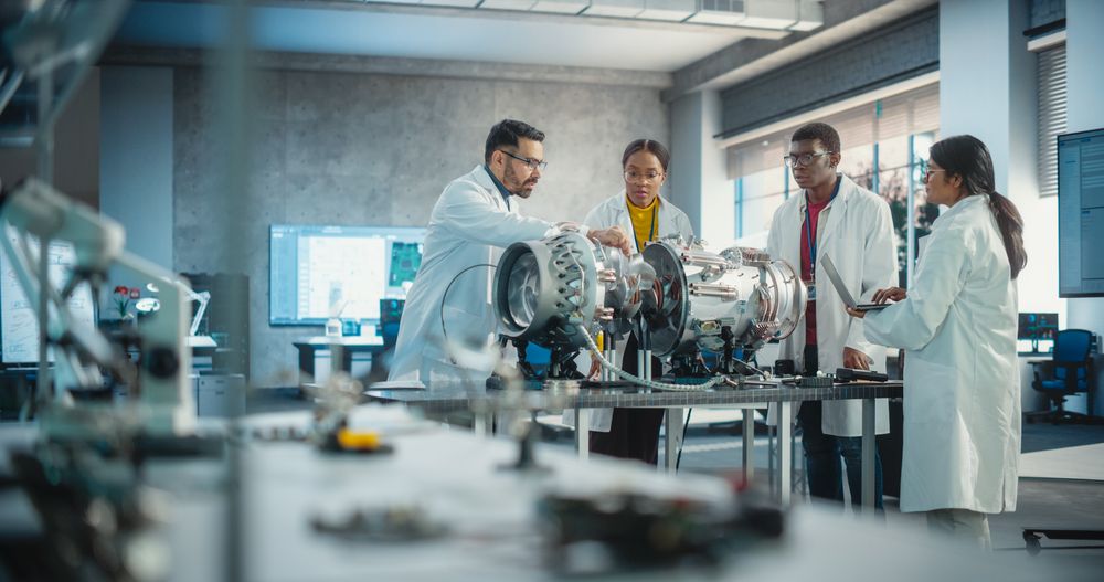 Young Female Black Engineer Leading her Team, Analyzing and Researching How a Futuristic Turbofan Motor Works.