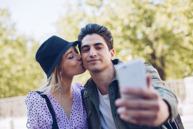 Happy young couple taking selfie in park