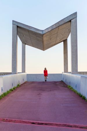 Back of woman in red coat standing under modern gazebo