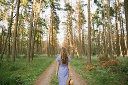 Young woman standing among pine trees