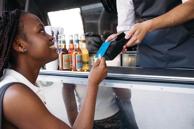 Happy woman paying food truck with tap card
