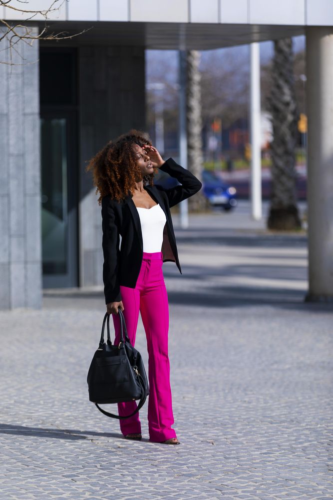 Female in bright pink trousers and handbag strolling outside