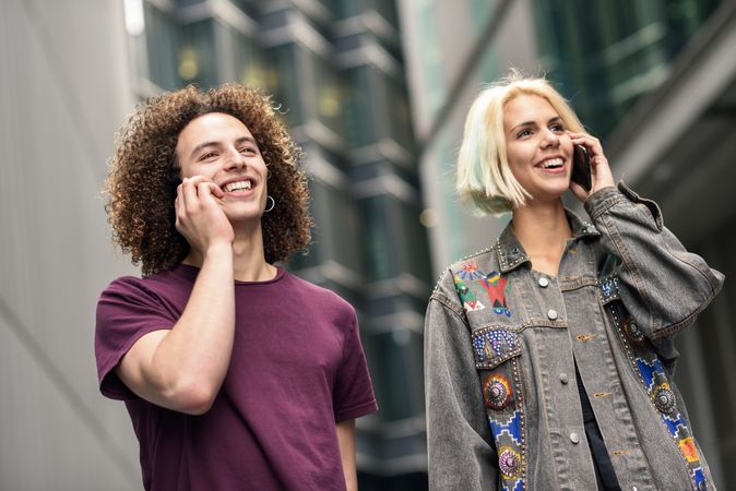 Male and female talking on cell phones walking on British city street