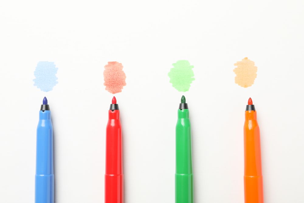 Four felt tipped markers writing on paper