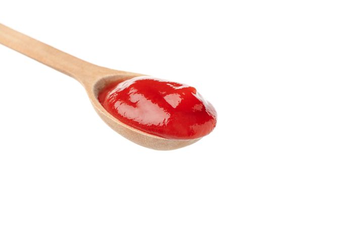 Wooden spoon with tomato sauce isolated on neutral background