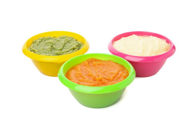 Bowls with healthy baby food isolated on plain background
