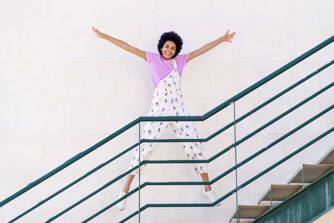 Happy woman jumping on stairs with green handrail