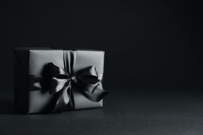 Gift box with dark bow on dark background