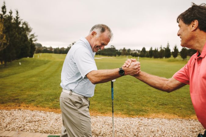 Two golf players shaking hands during a practice at driving range