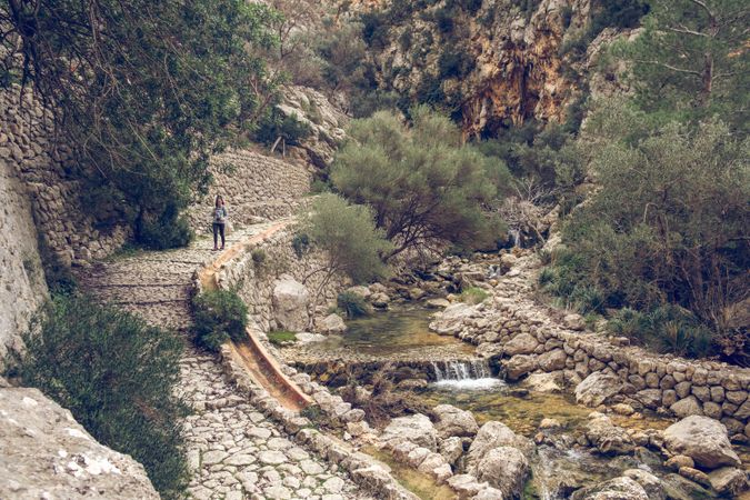 Woman on walkway near streaming creek in mountains
