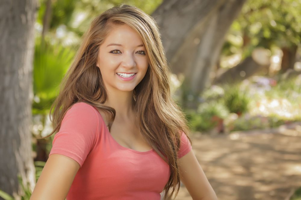 Portrait Of Smiling Asian Woman Standing In Park