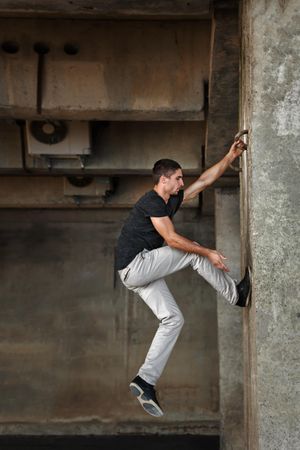 Male climbing up cement wall using hooks