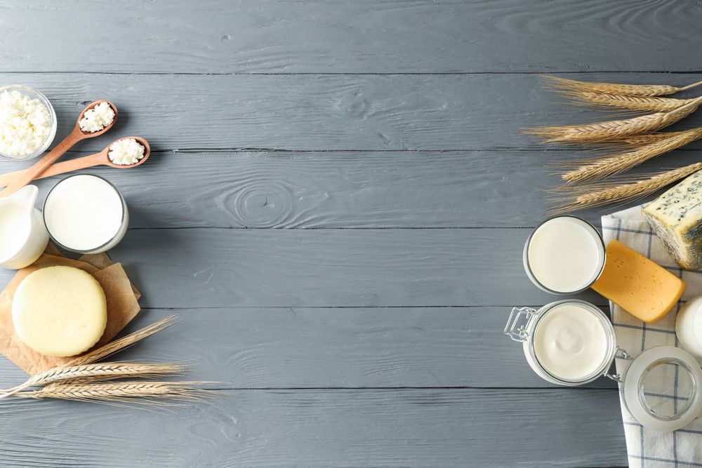 Flat lay. Different dairy products on grey wooden background, copy space