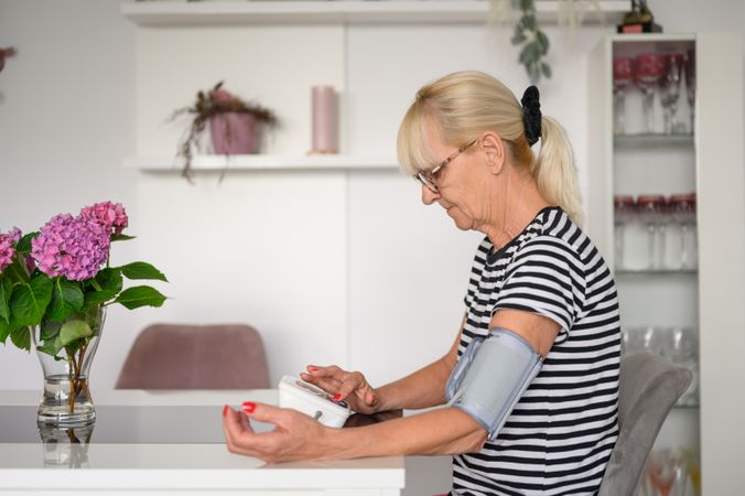 Mature woman measuring blood pressure at home