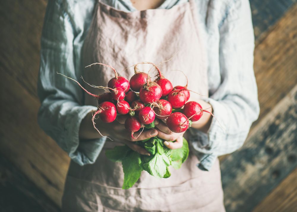 Woman holding bunch of root vegetables in her hands