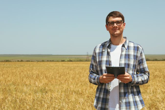 Young man with clipboard in barley field. Agriculture business