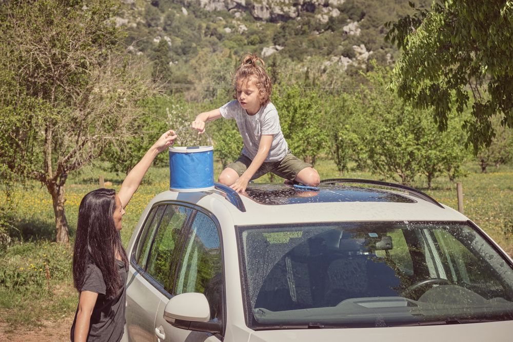 Happy woman with son washing car on sunny day